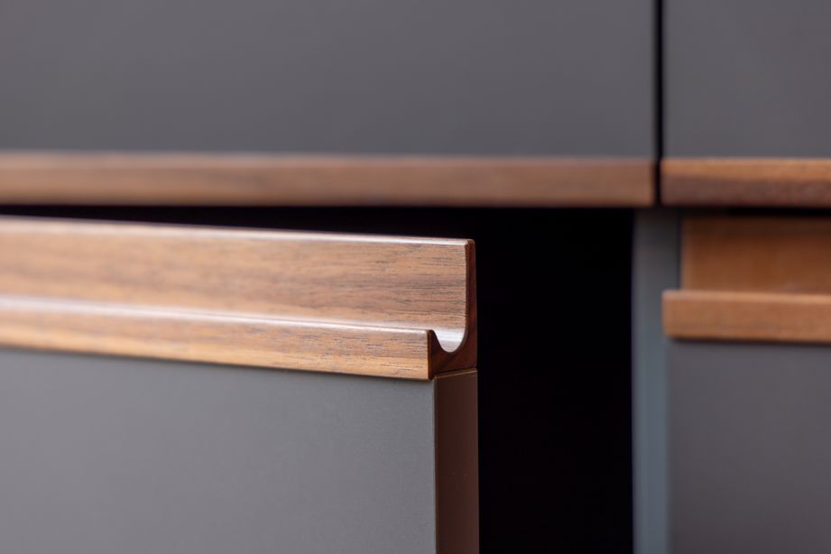 Detailaufnahme einer Küche mit FENIX Oberfläche und integrierten Griffleisten aus massivem Nussbaumholz.