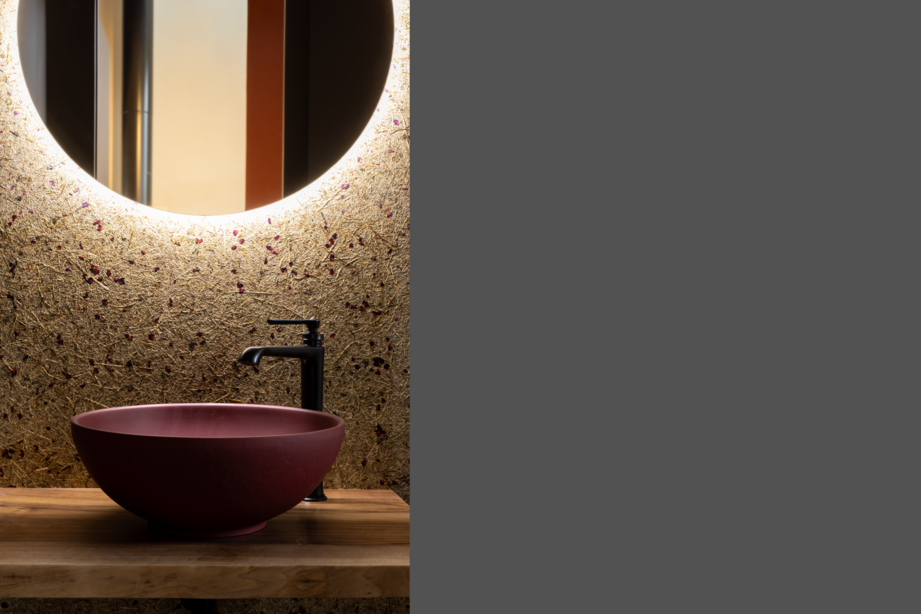 Waschbecken mit Spiegel im Badezimmer des Wohnscheunen-Neubaus, gestaltet mit natürlichen Materialien und warmem Licht.